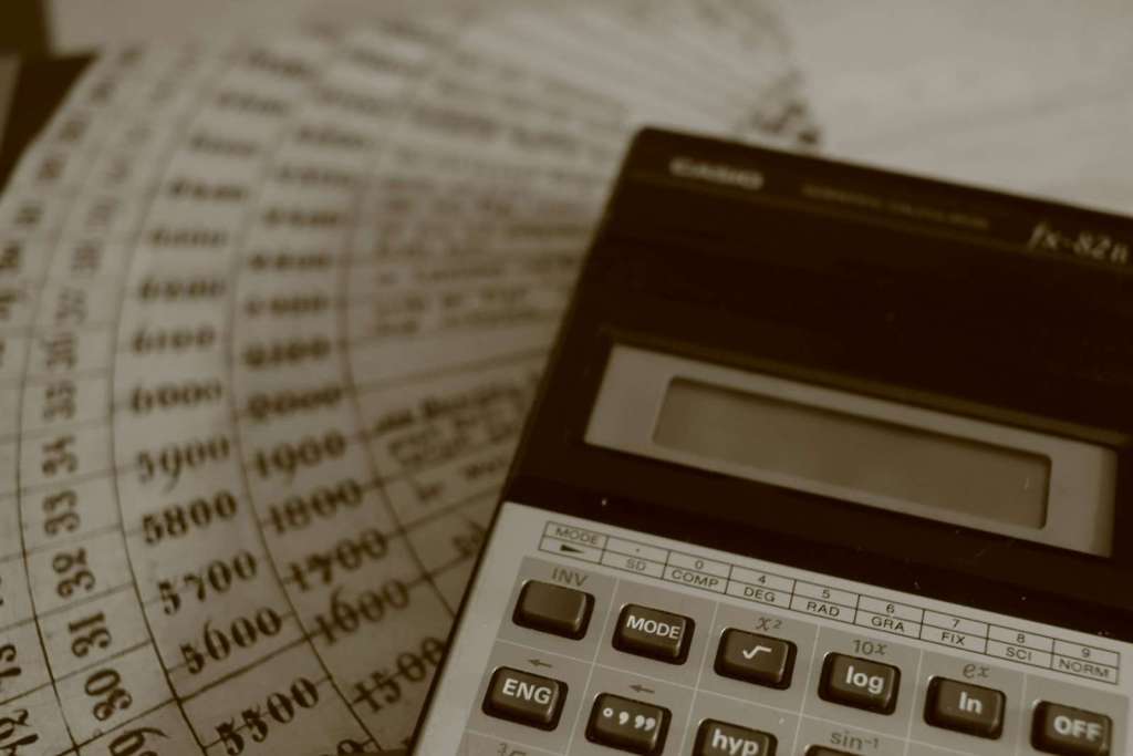 A calculator rests on old financial ledger sheets with numbers
